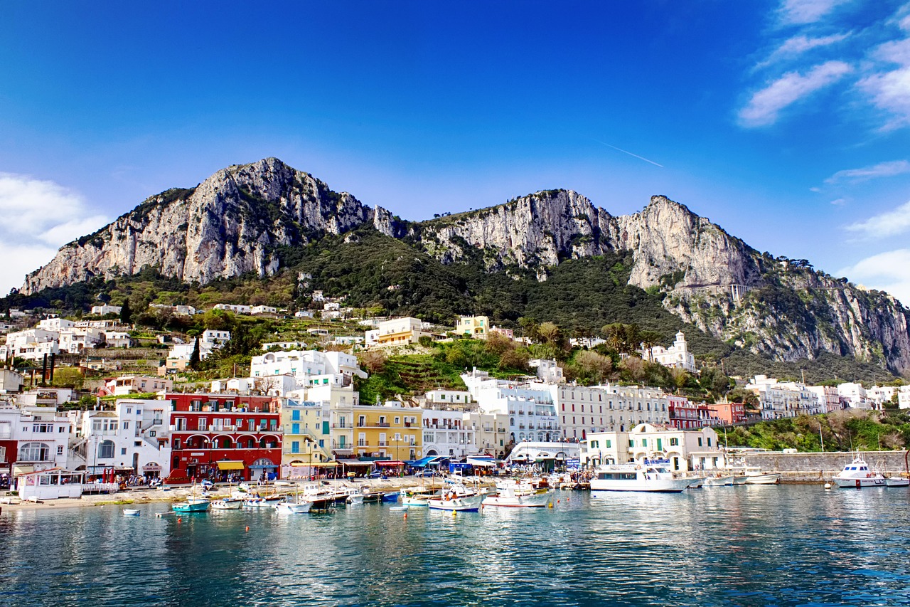 Marina Grande, the port of Capri, with colourful buildings along the waterfront and rocky mountains behind.