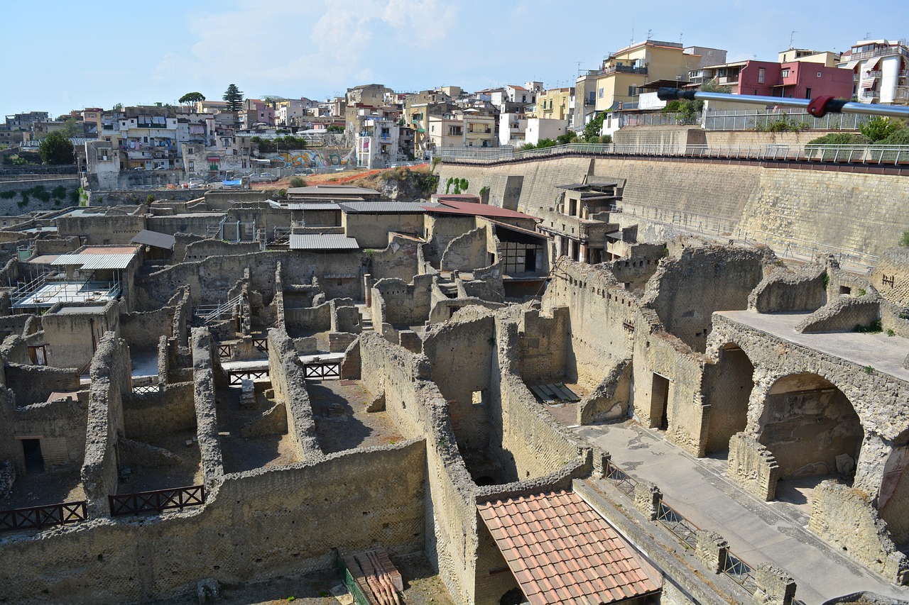The excavated ruins of Herculaneum seen from above, with the modern town of Ercolano rising behind them.
